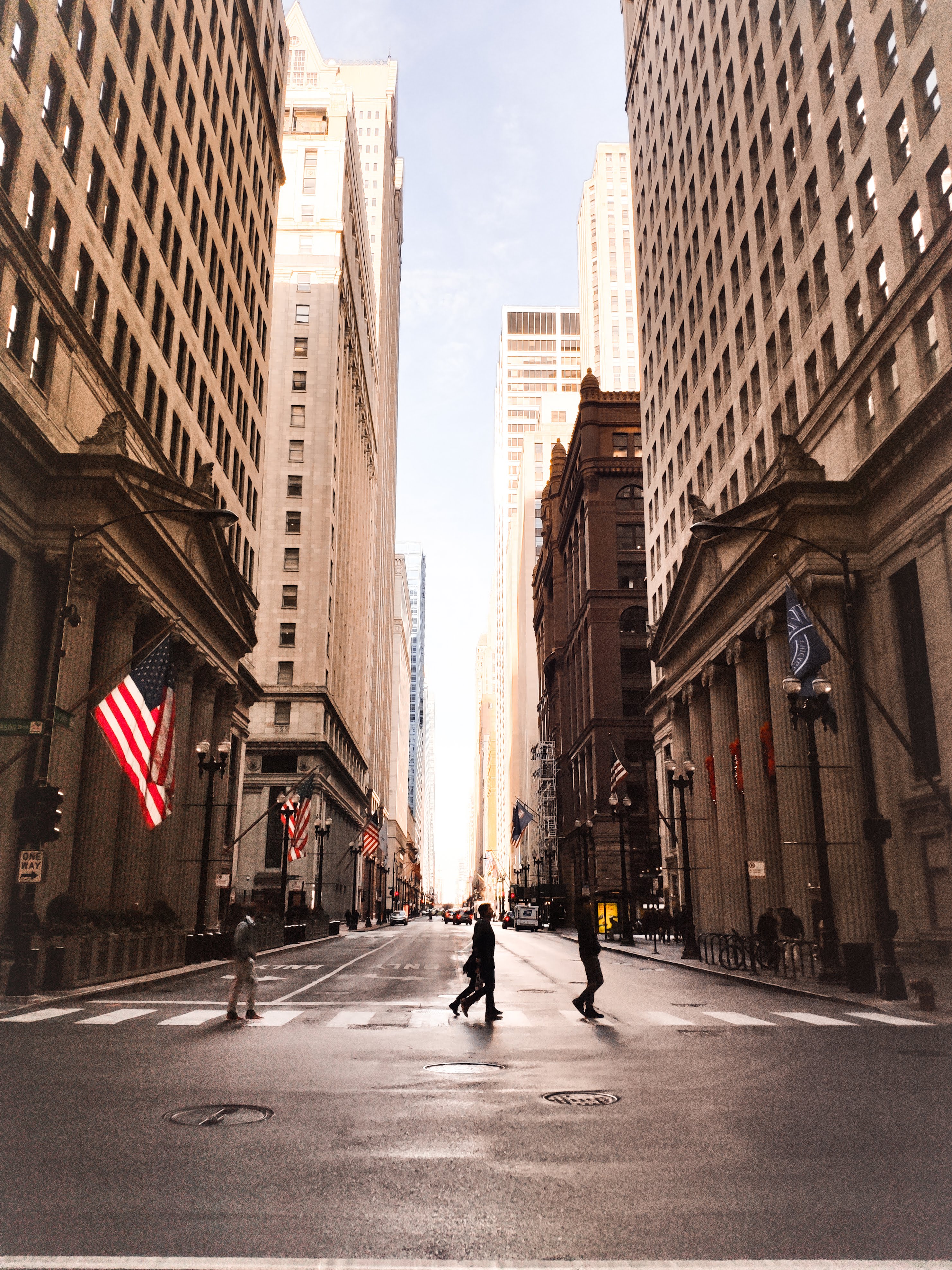 View of street and buildings with people walking across and American flag